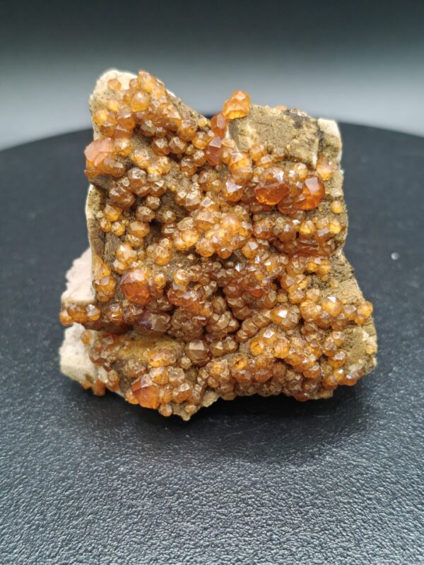 Spessartien-granaat op matrix met diep oranje kristallen en een natuurlijke, ruwe structuur.