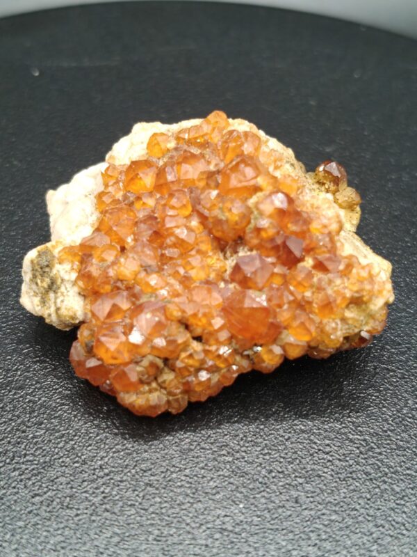 Spessartien-granaat op matrix met diep oranje kristallen en een natuurlijke, ruwe structuur.